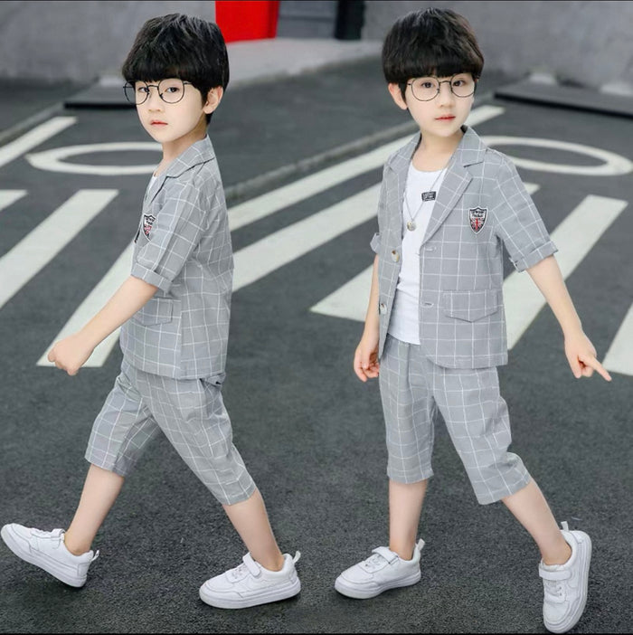 Two children wearing gray checkered suits on a street.