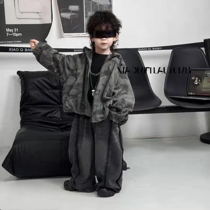 Person wearing a dark outfit with a hood in a modern indoor setting.