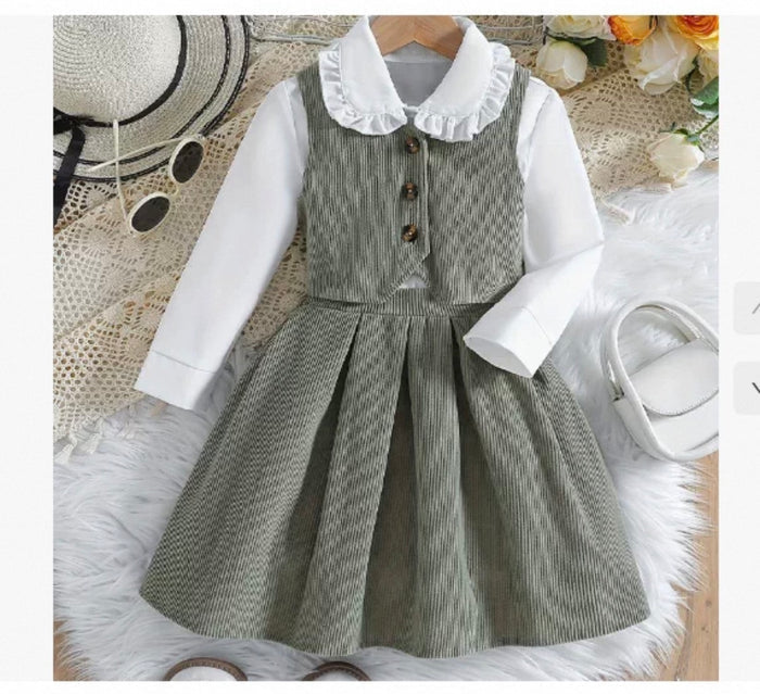 Children's outfit with gray checkered dress over white shirt on a textured surface.