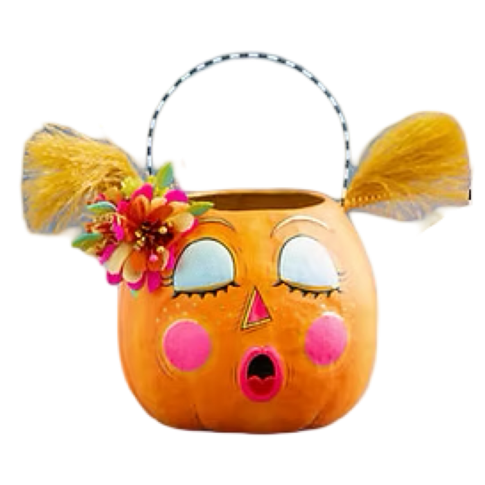 An orange pumpkin-shaped Halloween bucket basket with a handle, featuring cartoon eyes, pink cheeks, a surprised mouth, yellow feather-like hair accents, and a flower decoration on the side, isolated on a white background.