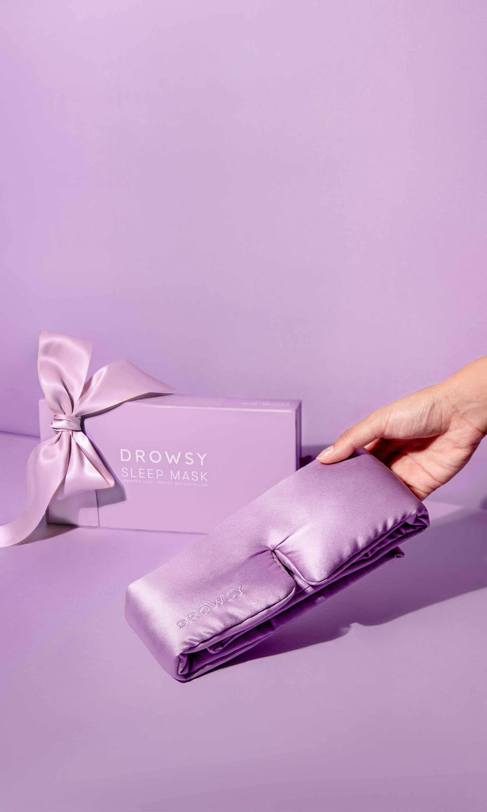 Folded purple satin pillowcase with a matching box and 'Drowsy' branding on a purple background.