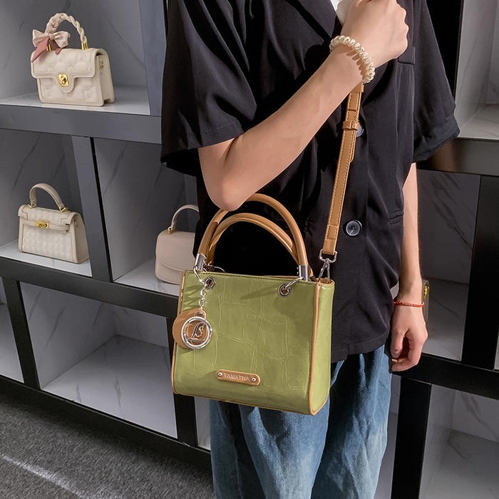 Person holding a green handbag with a shelf of handbags in the background