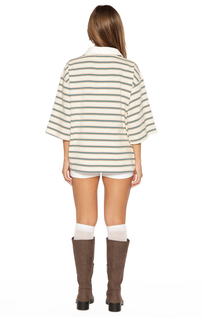 Rear view of the cream, green, and light brown striped polo shirt with a white collar and relaxed fit