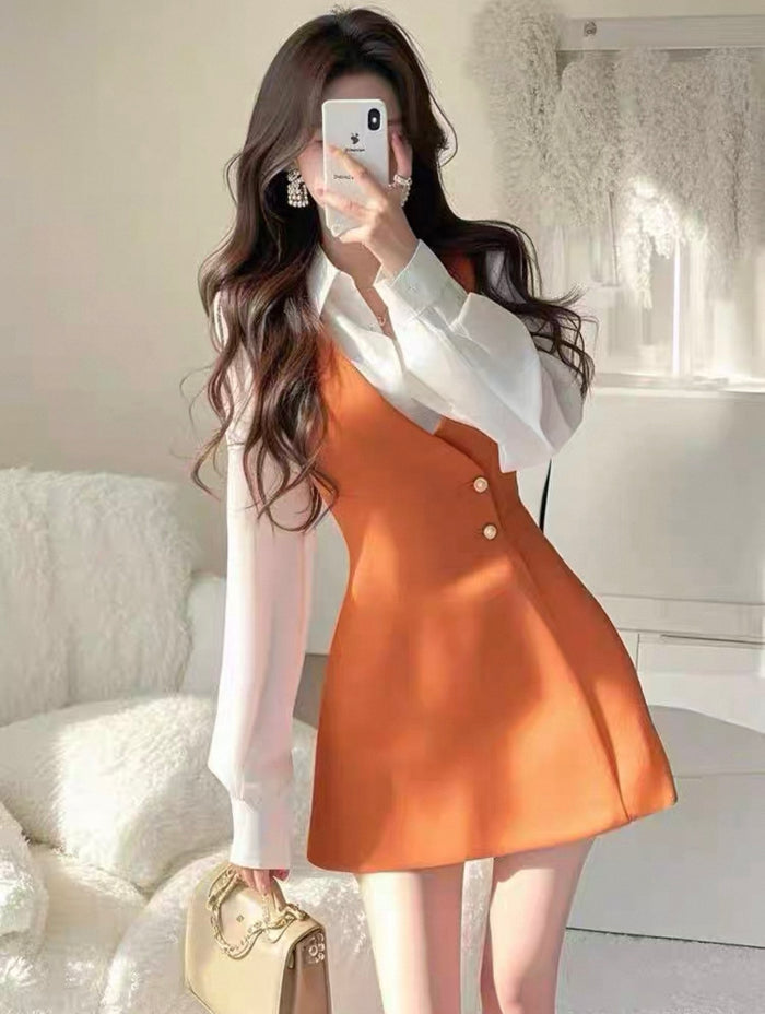 Woman taking a mirror selfie wearing a white blouse and orange dress.