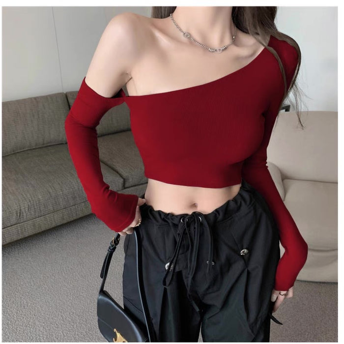 Person wearing a red one-shoulder top and black pants in an indoor setting.