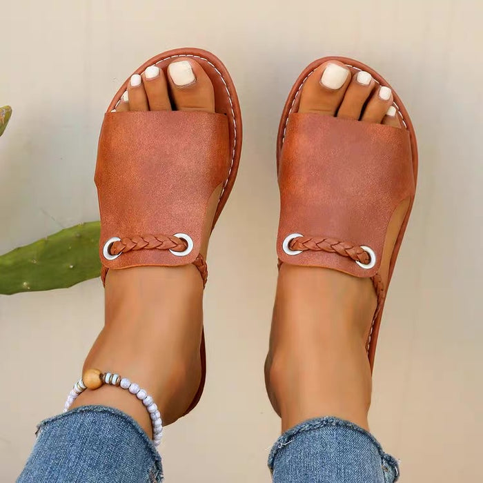 Brown sandals with braided straps worn by a person with blue jeans.