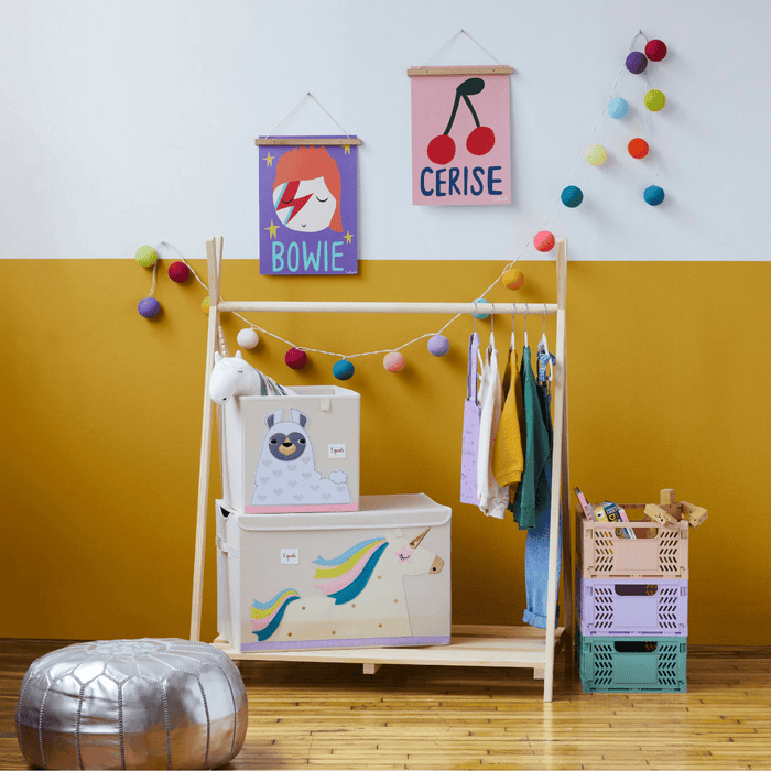 Children's room with a wooden wardrobe, colorful storage bins, and wall decorations.