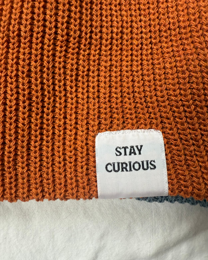Close-up of an orange knitted fabric with a white label displaying text.