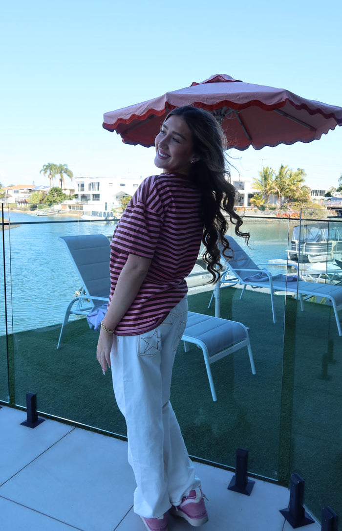 Side view of a pink and maroon horizontal striped oversized tee with short sleeves