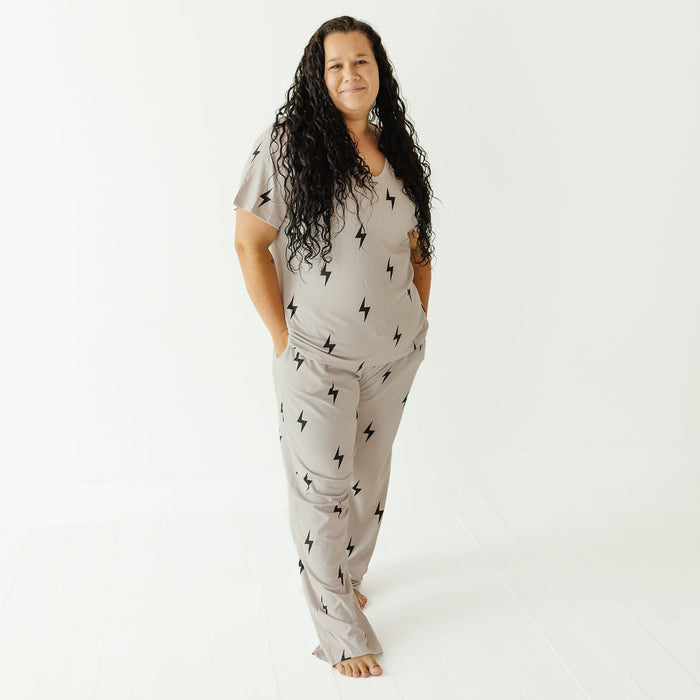 A woman modeling a light gray two-piece pajama set with a black lightning bolt pattern, standing against a plain white studio background.
