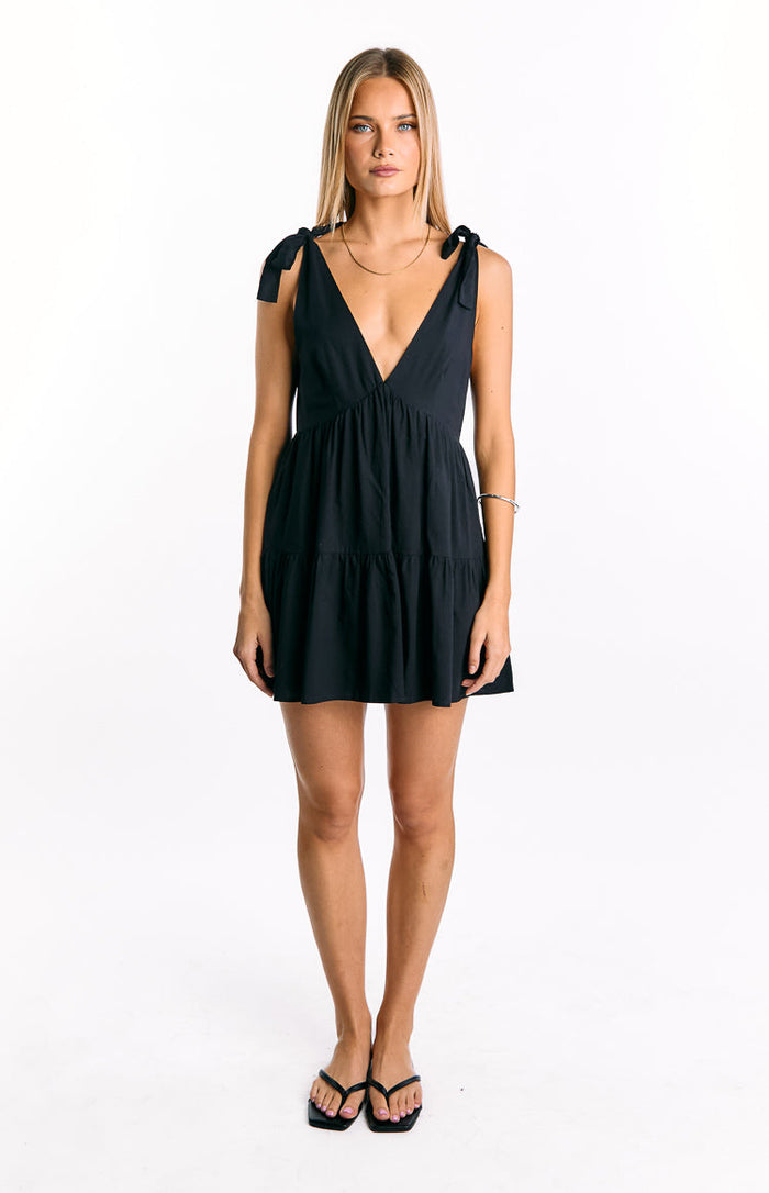 Black relaxed fit mini dress with a deep V-neck, tie-shoulder straps, and a tiered skirt