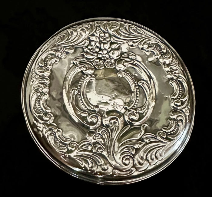 Decorative silver plate with intricate designs on a black background