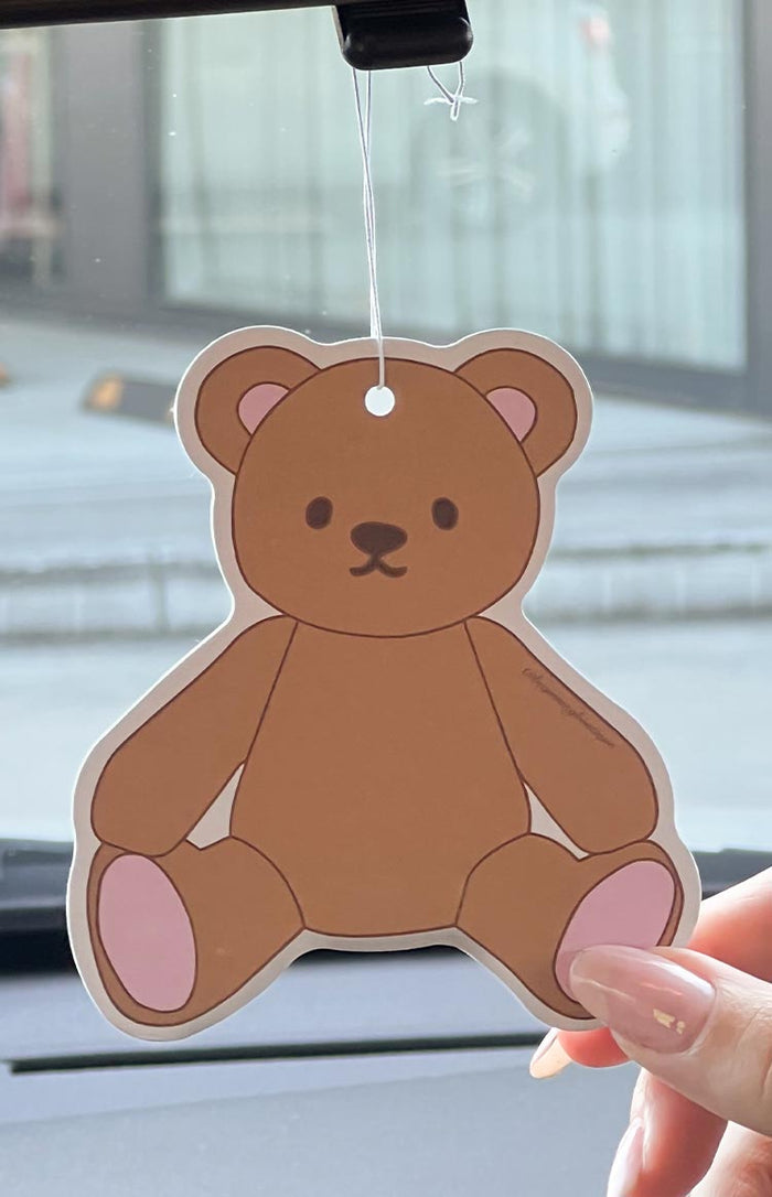 teddy bear shaped car air freshener hanging from rear view mirror