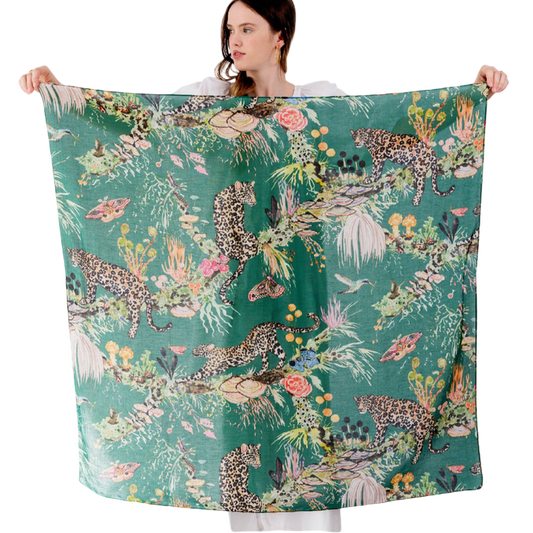 Person holding a large scarf with a jungle-themed design featuring leopards and foliage.
