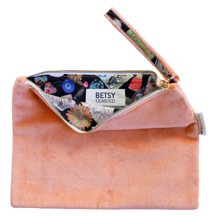 Pink velvet clutch with floral lining and 'Betsy Olmsted' label on a white background