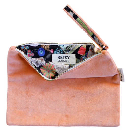 Pink velvet clutch with floral lining and 'Betsy Olmsted' label on a white background