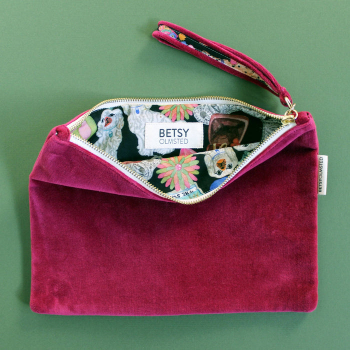 Pink velvet clutch bag with a colorful interior on a green background