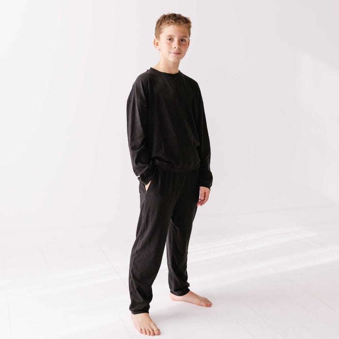 Child wearing a black pajama set on a white background