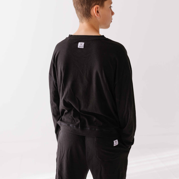 Person wearing a black outfit with a logo on a white background