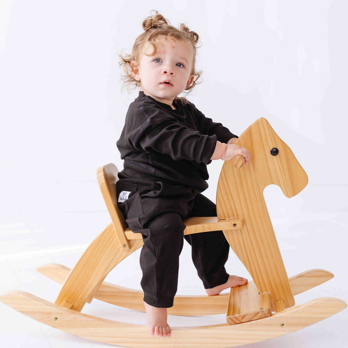 Child sitting on a wooden rocking horse against a white background