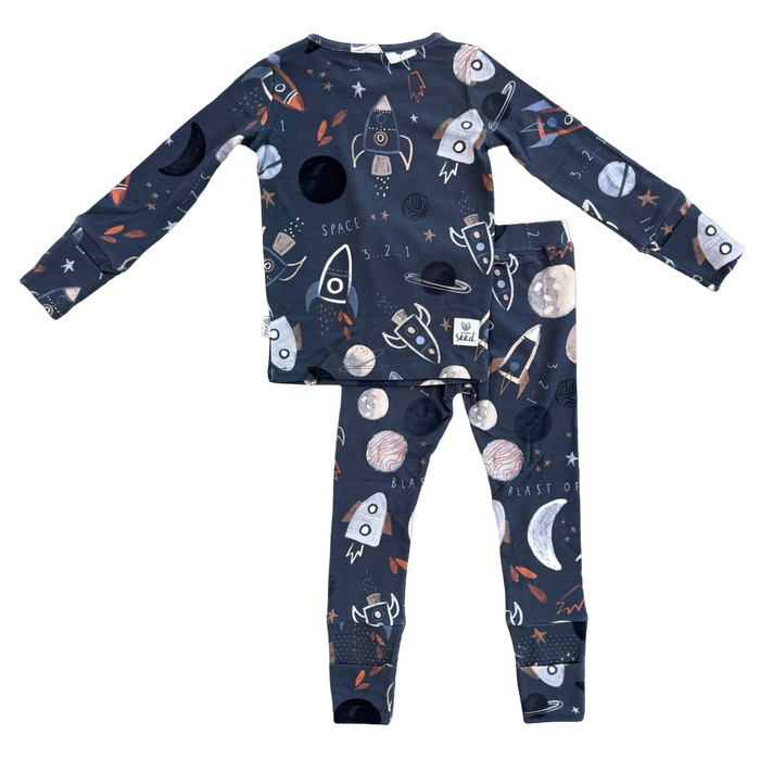 A two-piece children's pajama set featuring a long-sleeve top and matching pants in dark navy blue with a playful space-themed print of rockets, moons, planets, and stars.