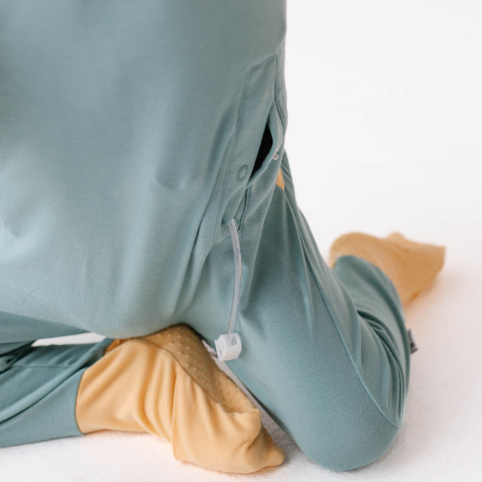 Person wearing teal pants with beige foot covers on a white background