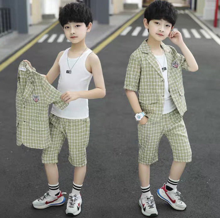 Two children wearing matching green checkered outfits on a road.