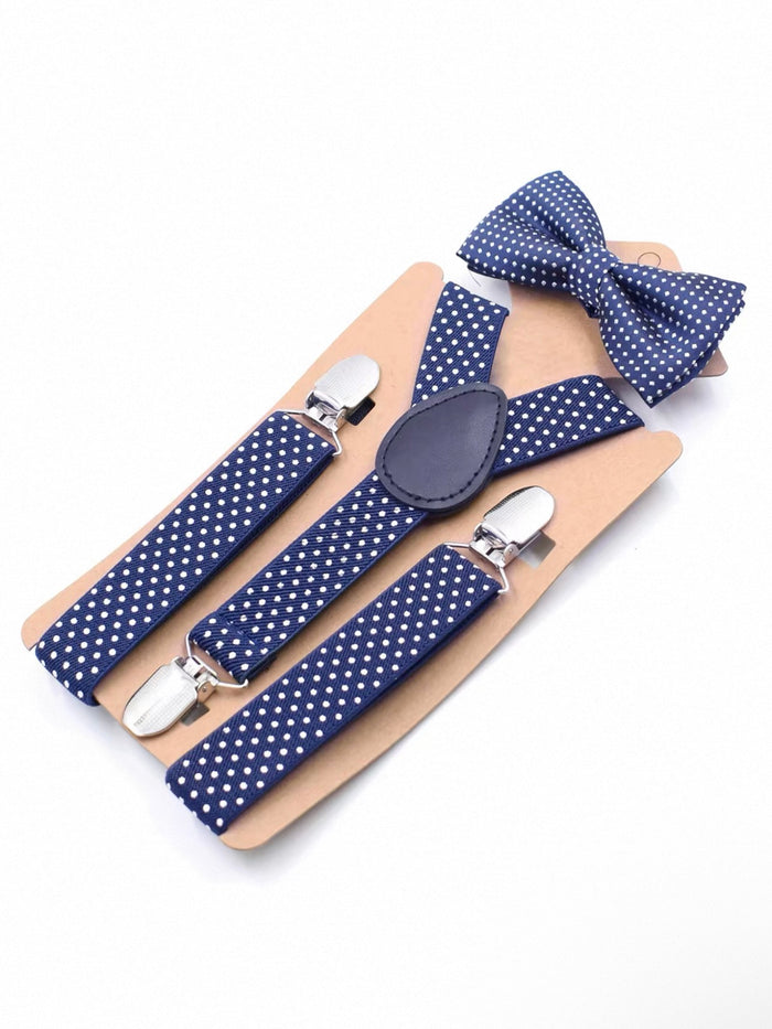Navy blue suspenders with white polka dots and matching bow tie on a wooden board.