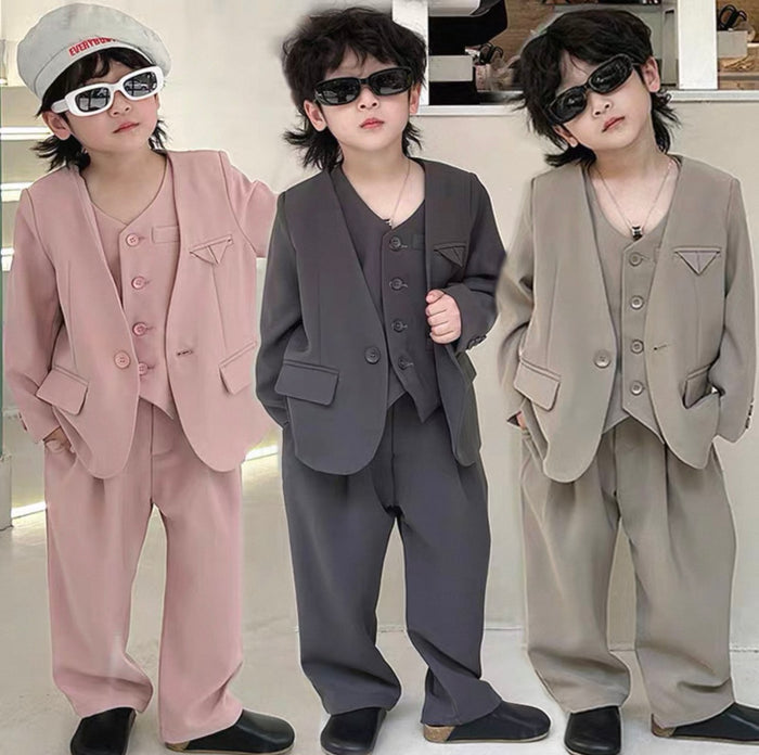 Three children wearing different colored suits in a studio setting.