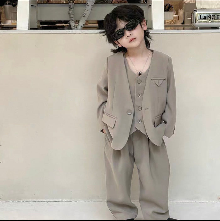 Child wearing a beige suit and sunglasses in an urban setting