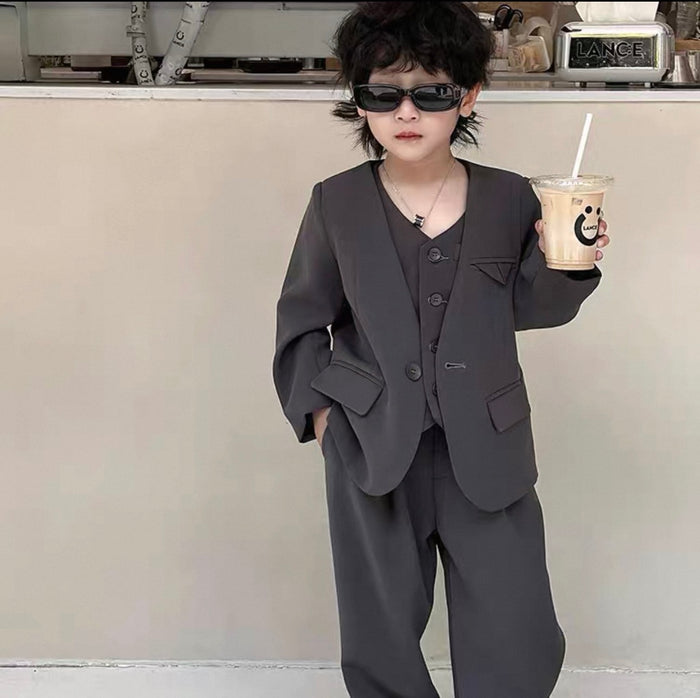 Child in a dark suit holding a drink in a kitchen setting