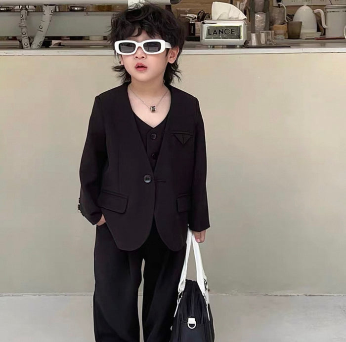Child wearing a black suit and sunglasses in an indoor setting