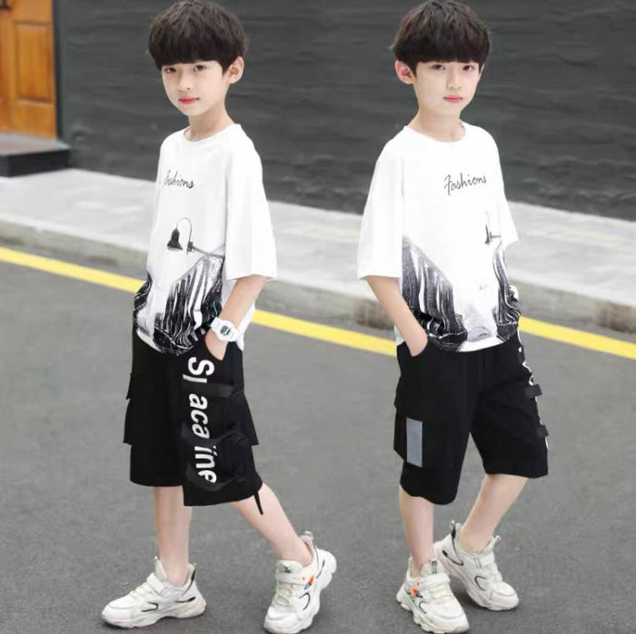 Two children wearing matching outfits with white t-shirts and black shorts on a street.