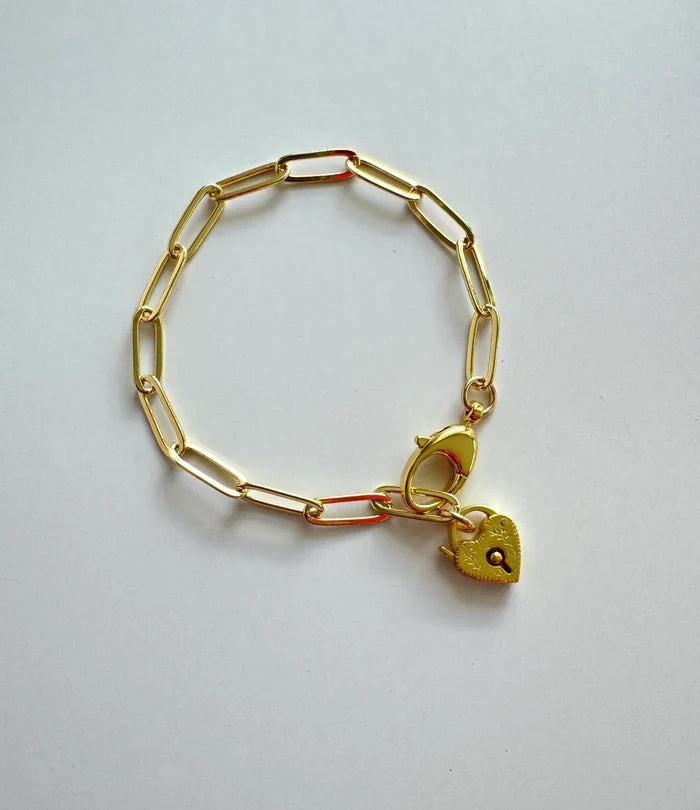 Gold bracelet with a heart-shaped padlock charm on a light gray background