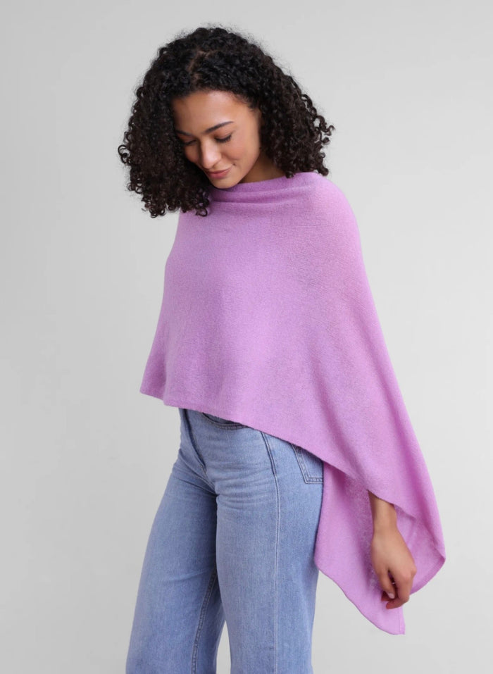 Woman wearing a light purple poncho over a gray background