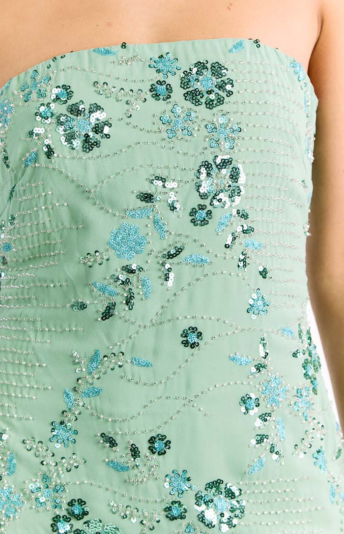 Close-up of the mint green strapless dress, showing teal and light blue sequin floral patterns with silver bead details