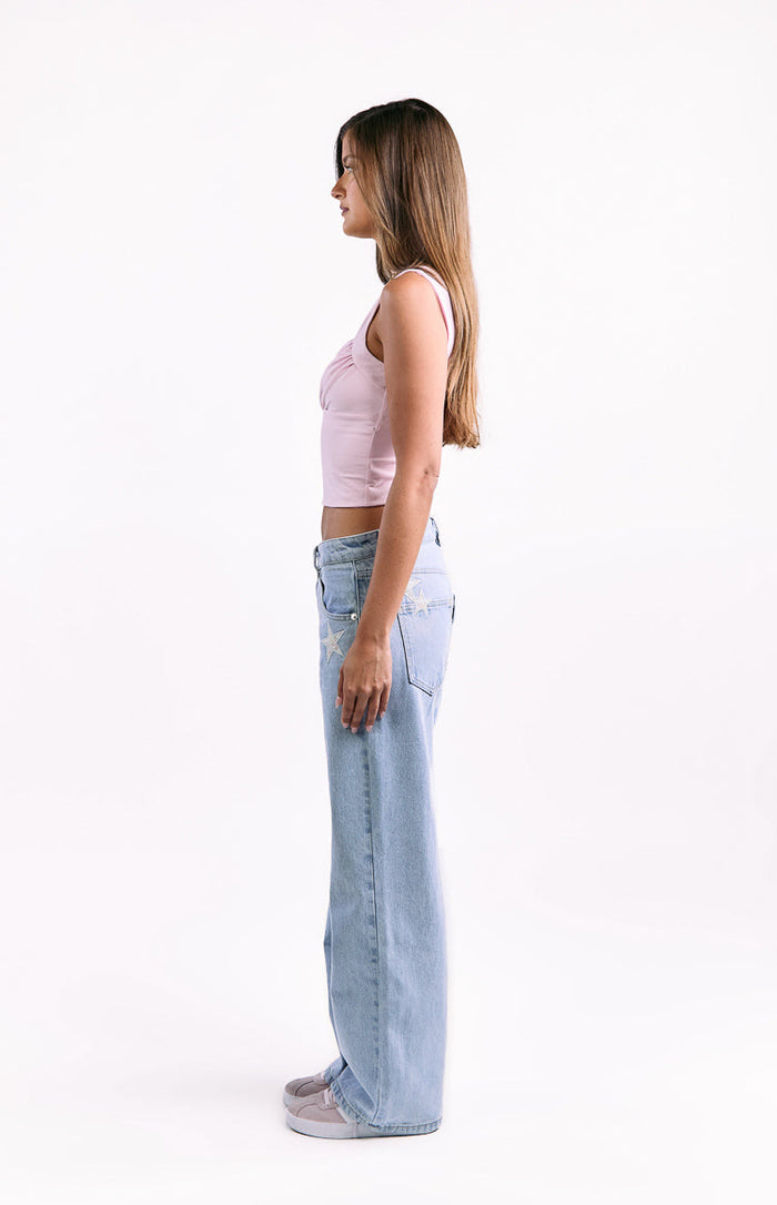 Side view of light wash low waist baggy leg jeans with star embroidery on the hip