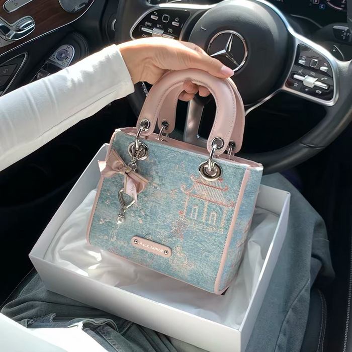 Handbag with decorative elements held by a person inside a car.