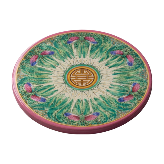 Round sandstone coaster with a pink border, green bok choy-inspired pattern, and dragonfly details on a marble surface.