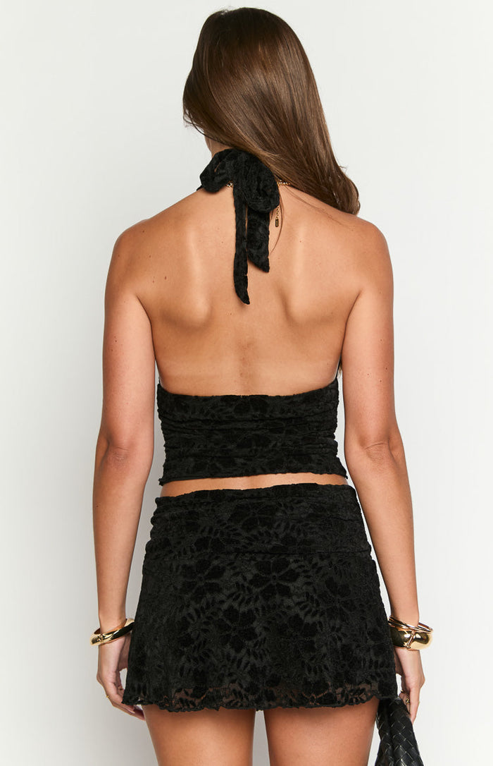 Rear view of a black crushed velvet crop top with a halter neck tie at the back