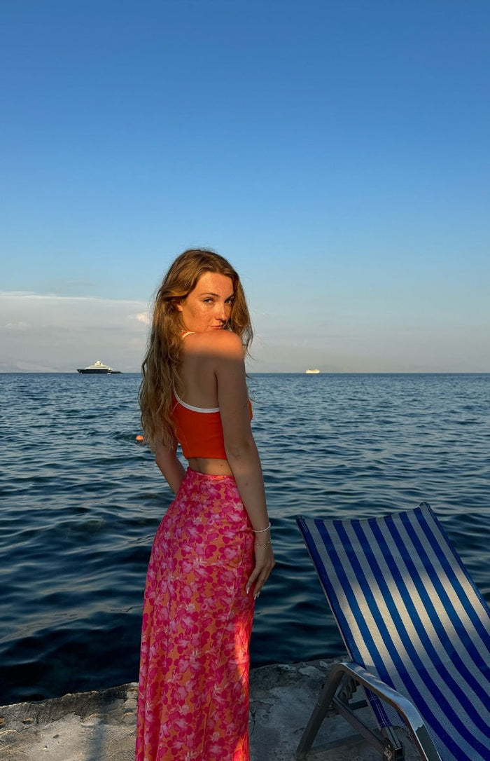 Rear view of an orange and pink floral satin maxi skirt with a flowy silhouette