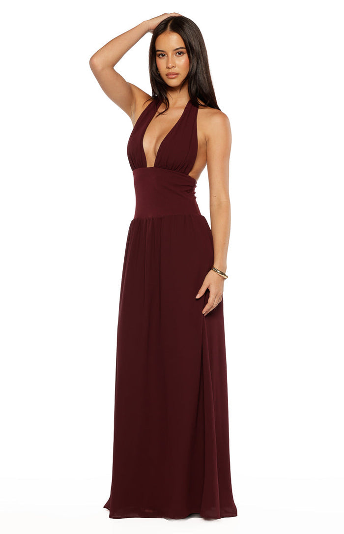 Side view of a burgundy deep V-neck halter maxi dress with a fitted waist and side cutouts