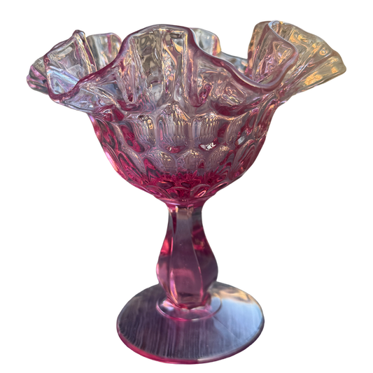 Pink glass candy dish with scalloped edge on a white background