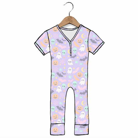 A short-sleeve baby jumpsuit with a light purple background and a Halloween print featuring ghosts, pumpkins, bats, and moons, hanging on a wooden hanger against a white background.