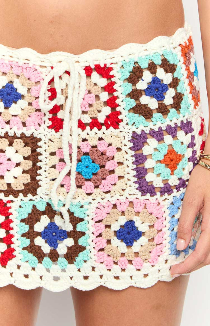 Close-up of the multi-coloured granny square crochet mini skirt, showing drawstring waist and scalloped hem