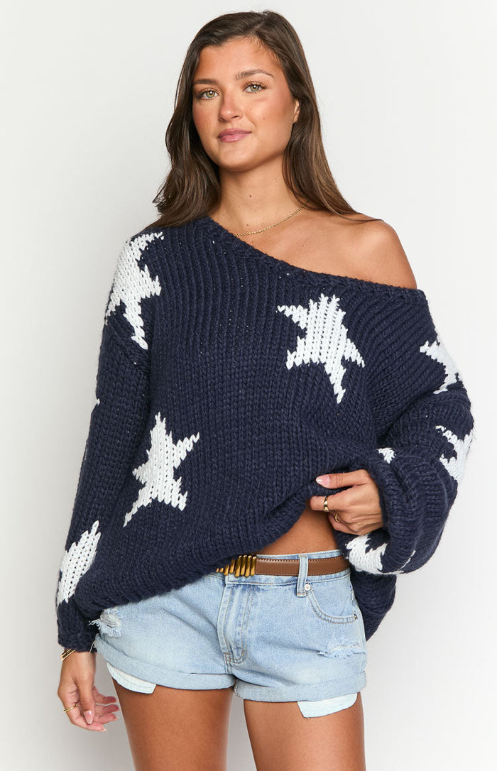 Oversized navy chunky knit sweater with white star pattern and wide off-shoulder neckline