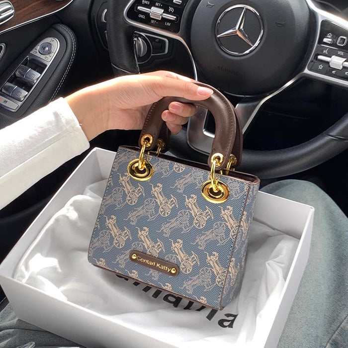 Hand holding a patterned handbag in front of a Mercedes steering wheel