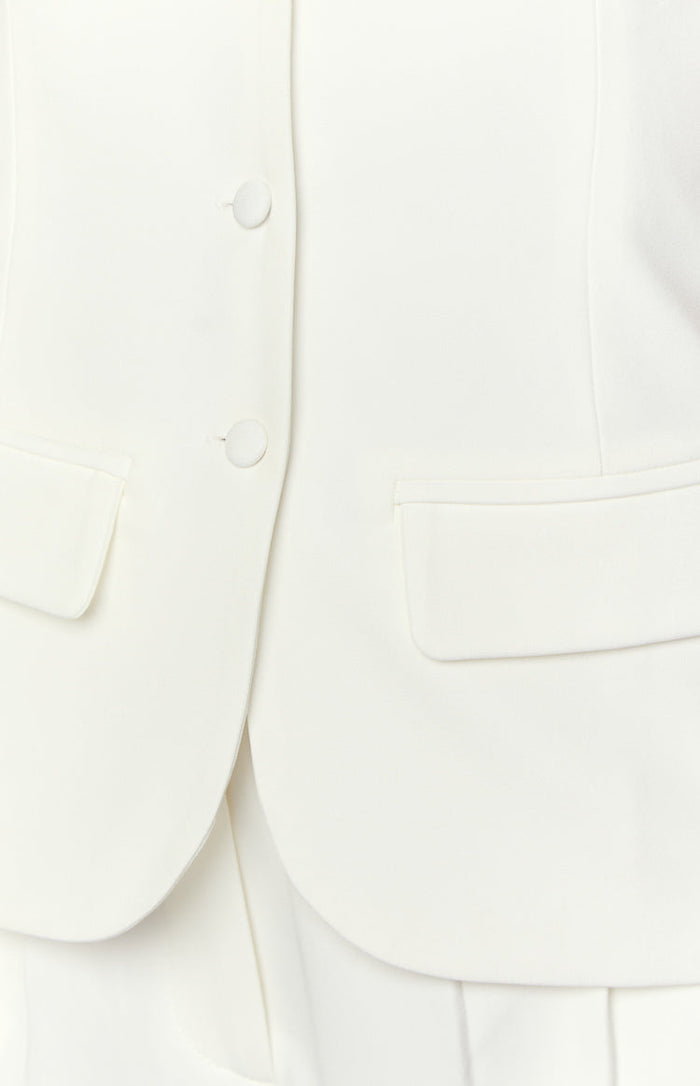 Close-up of the white button-up top with two front buttons and a single flap pocket