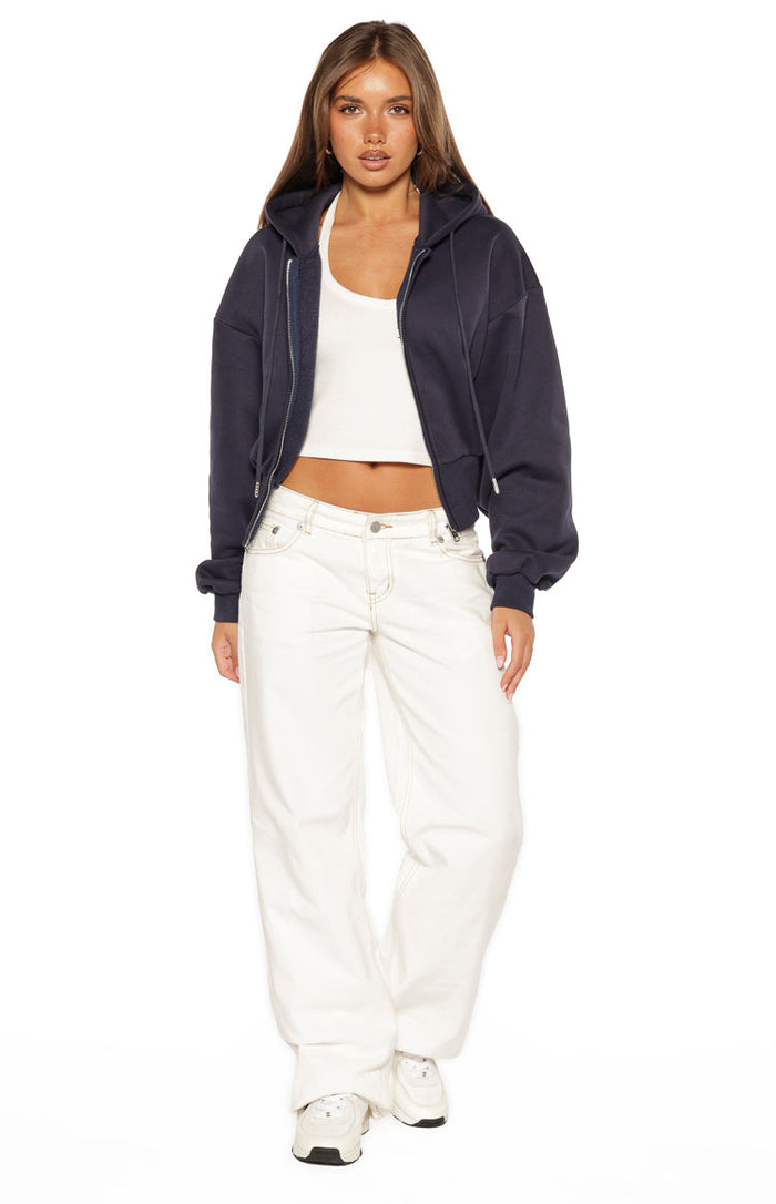 Front view of a navy zip hoodie sweater, worn open to show its cropped length and relaxed fit