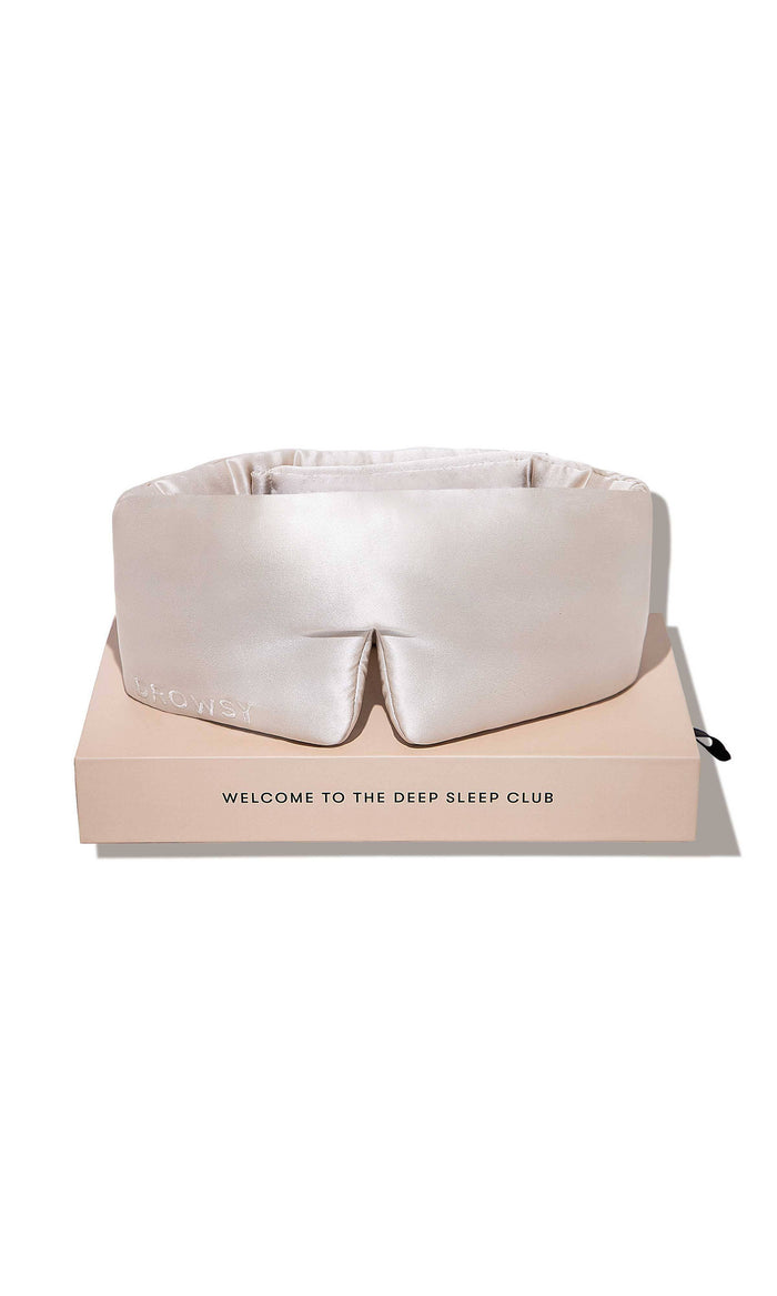 White sleep mask on a pink box with 'The Deep Sleep Club' branding on a white background